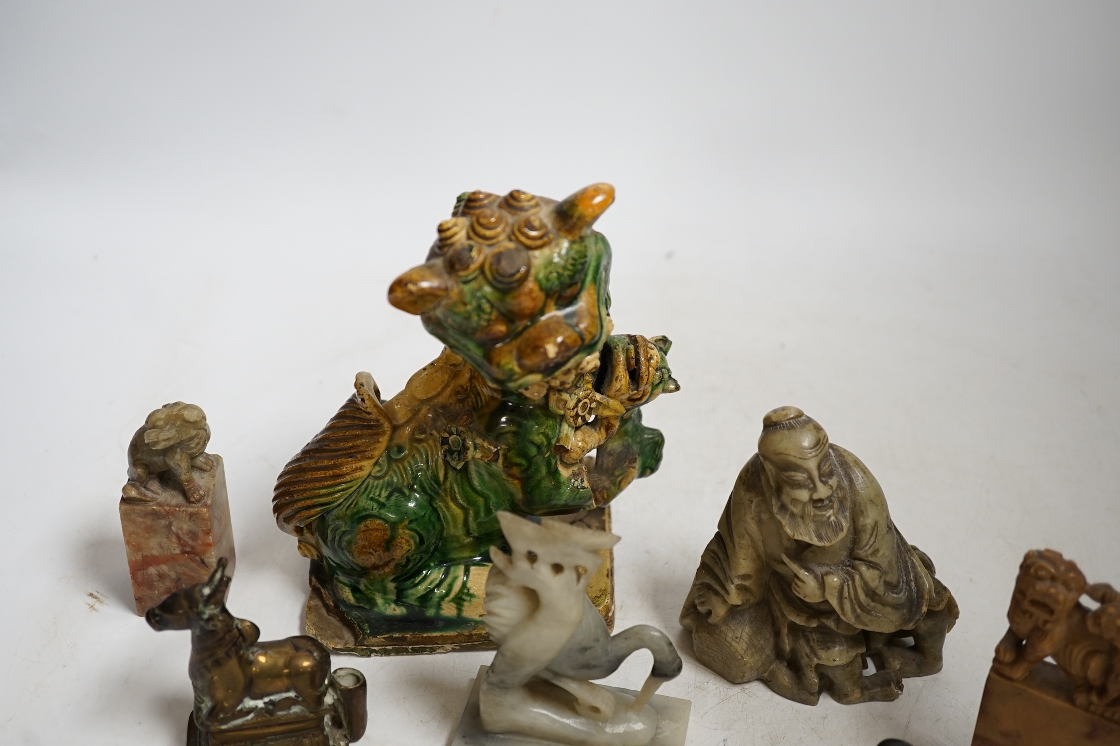 A glazed Chinese lion dog and a collection of soapstone carvings including seals, largest 17cm high. Condition - varies, poor to fair